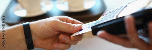 Male hand inserts plastic credit bank card into payment terminal