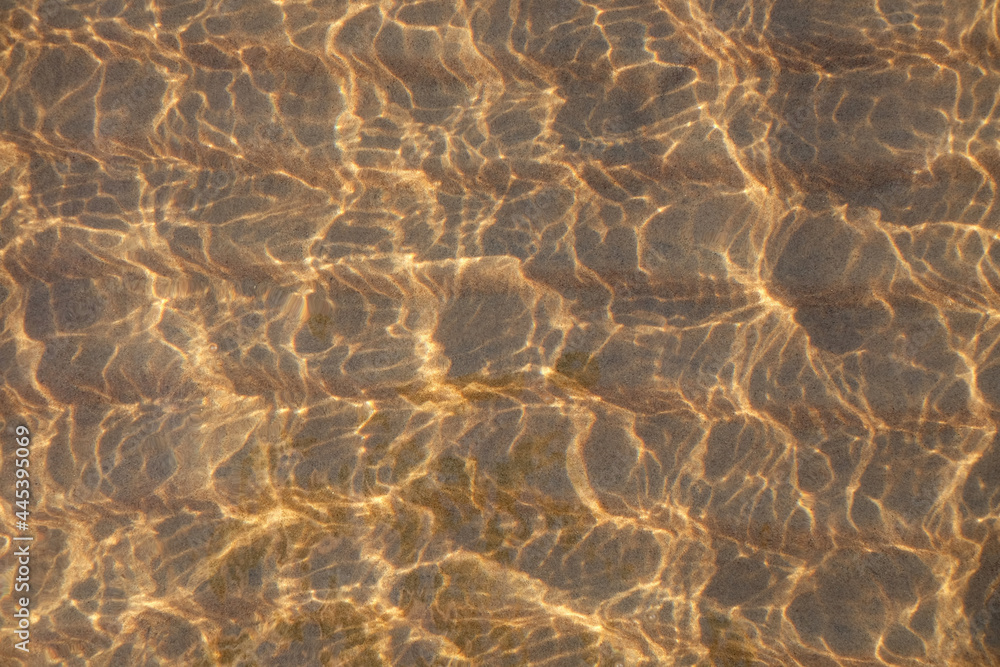 Fototapeta View through the water and waves on the sand with sunlight, abstract natural background