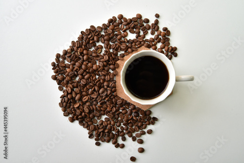 Coffee in a cup and scattered coffee beans on a white background, top view