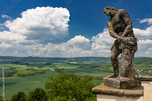 Baroque statues the scourging of Christ a overlooking the landscape with a face from cloud, Czechia