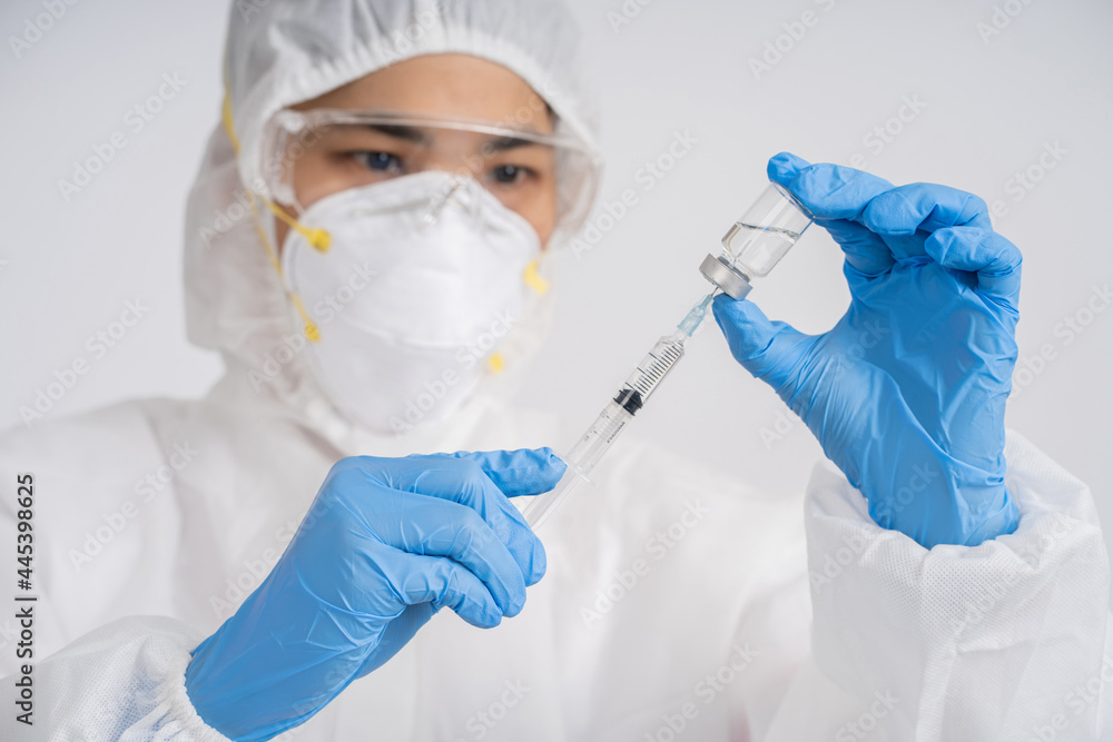 Doctor wearing a medical mask holds a syringe containing a vaccine to treat coronavirus. Doctor wearing a medical mask holds a syringe containing a vaccine to treat coronavirus.