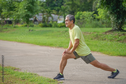 elderly retired man is stretching his legs before running or jogging, concept warm up exercise prevent injury in elderly people