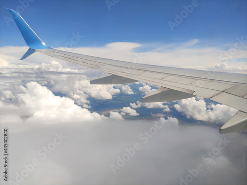 View from the plane of an airliner from a height to the ground with a view of the city in summer against the background of a blue sky with white clouds on a sunny day