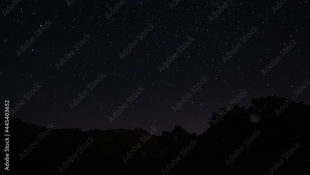 Timelapse of moving star trails in night sky. A view of the stars of the Milky Way with a mountain top in the foreground. Night sky nature summer landscape. Perseid Meteor Shower observation. Timelapse of moving star trails in night sky. A view of the stars of the Milky Way with a mountain top in the foreground. Night sky nature summer landscape. Perseid Meteor Shower observation.