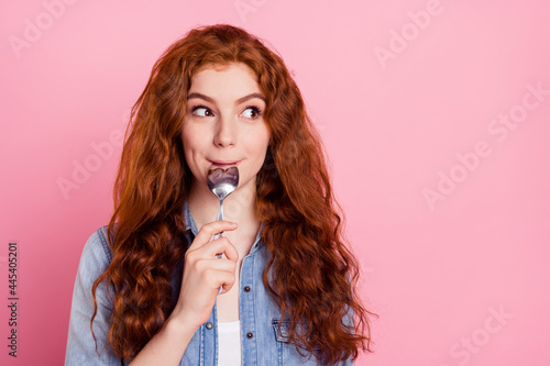 Photo of dreamy hungry young woman look empty space lick spoon isolated on pastel pink color background