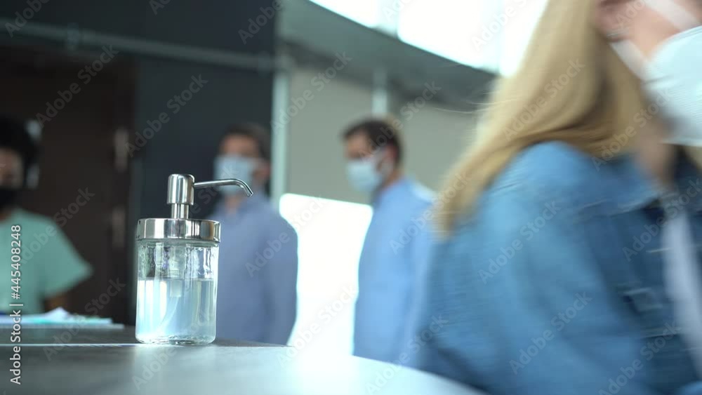 Coworkers wearing protective face mask using sanitize alcohol gel against corona virus. Coworkers wearing protective face mask using sanitize alcohol gel against corona virus.