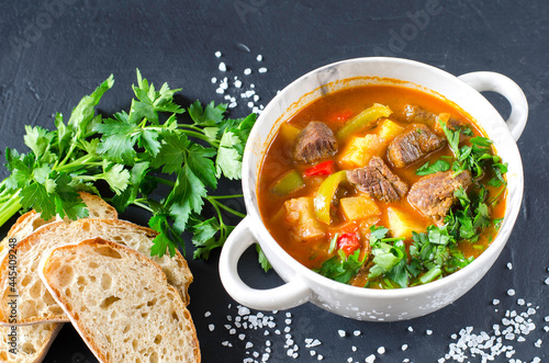 Traditional hungarian goulash with meat and vegetables on the black background