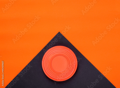 Orange clay target on black and orange geometric background. Skeet shooting. Copy space photo