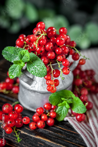 Ripe red currant berries in a bowl. Fresh red currants on dark rustic wooden table. Background with copy space. Selective focus. photo
