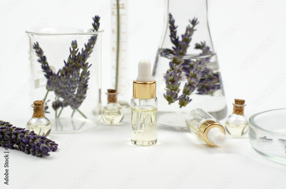 A bottle of lavender oil and medical flasks with lavender flowers on a white background. Moisturizing skin care