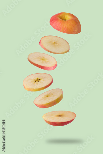 Sliced red apple flying on light green background. Levitation of fruit floating in the air. Creative minimal concept .