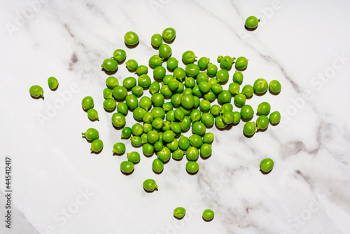 Raw green peas lying on marble surface photo