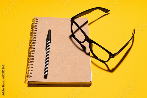 Studio shot of eyeglasses, pen and note pad from recycled paper photo