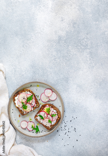 Healthy toasts of rye whole-grain bread with sunflower, flax and pumpkin seeds with cottage cheese (goat or ricotta), olive oil, fresh radishes, parsley and black and white sesame
