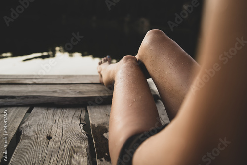A beautiful fashion background with sexy long legs in a wooden pier on the lake. 