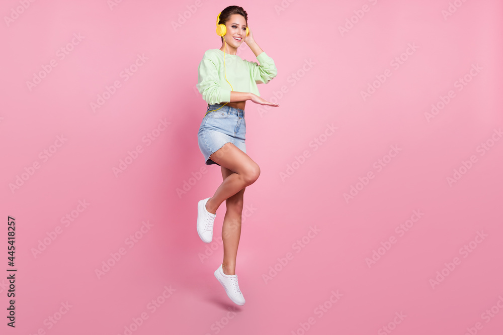 Full size profile side photo of young girl happy positive smile music dj earphones jump isolated over pastel color background Full size profile side photo of young girl happy positive smile music dj earphones jump isolated over pastel color background