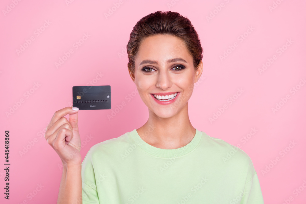 Photo of positive happy nice young woman hold hands credit card smile money isolated on pink color background Photo of positive happy nice young woman hold hands credit card smile money isolated on pink color background