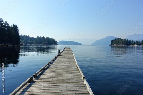 A beautiful view of a long empty dock extending into the ocean waters of the sunshine coast, in Egmont, British Columbia, Canada © christopher
