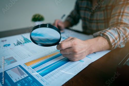 Businessman or Auditor Hand Looking At Tax Fraud Investigation, accounting records, financial statement, Internal audit, Through Magnifying Glass. Audit Concept.
