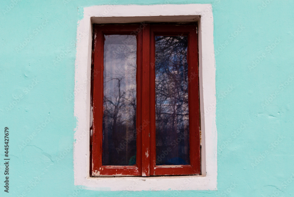 Traditional wooden window of a rustic house. Brown wooden window and a light blue wall Traditional wooden window of a rustic house. Brown wooden window and a light blue wall