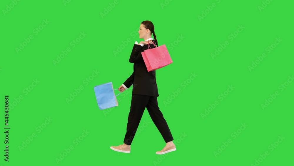 Young woman in office suit walks with color bags in her hands on a Green Screen, Chroma Key. Young woman in office suit walks with color bags in her hands on a Green Screen, Chroma Key.