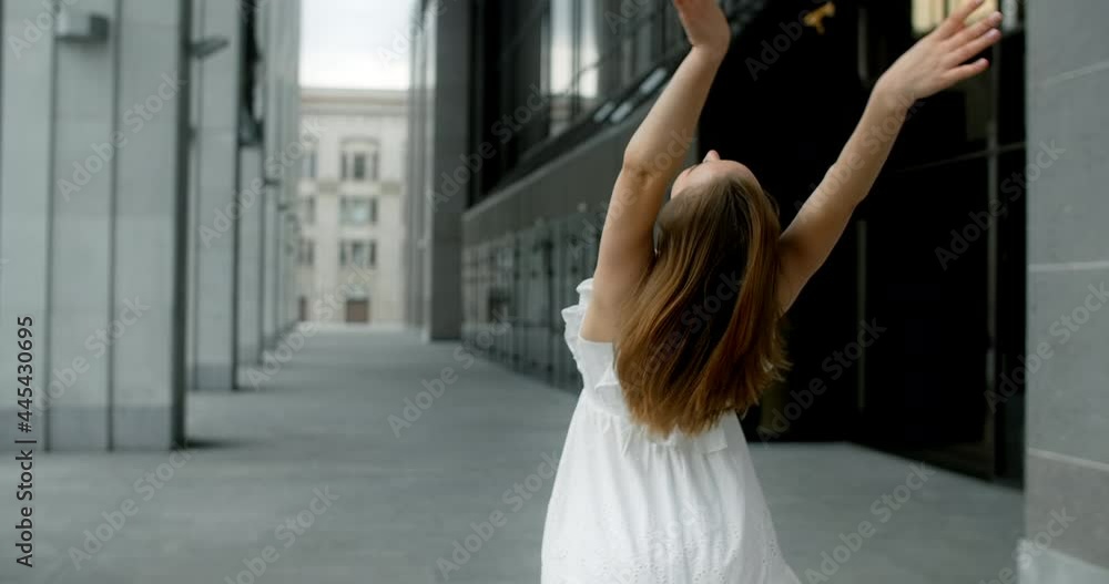 Young balerina in white dress runs through the gallery of columns in