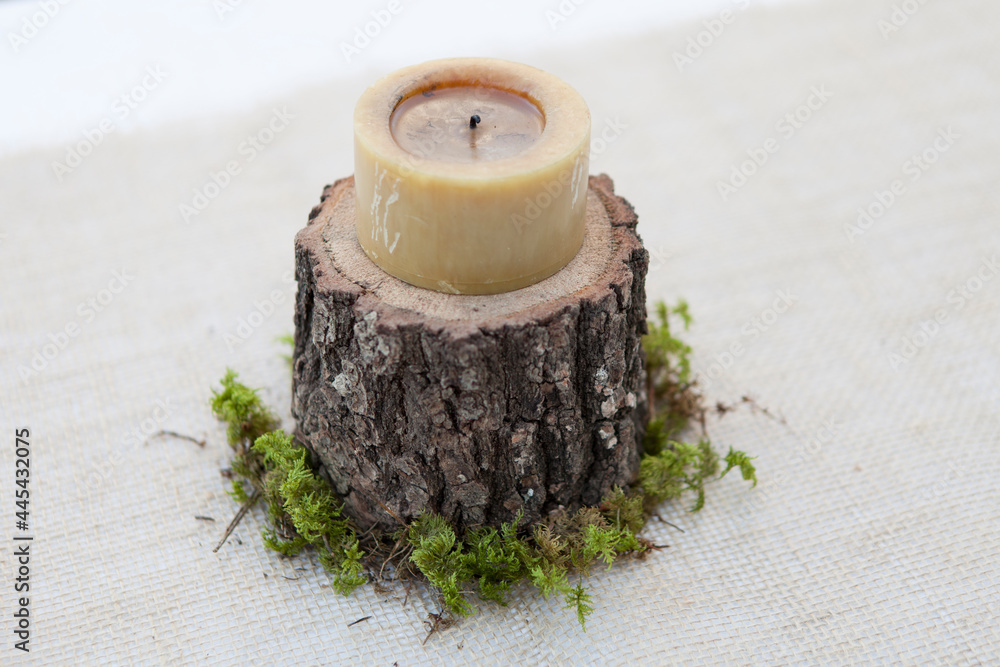 vela natural sobre un tronco cortado para levantar la vela de la mesa con un poco de musgo en el mantel  - obrazy, fototapety, plakaty 