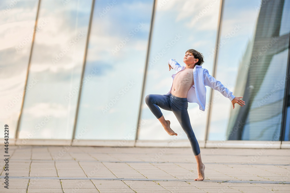 ballet boy teenager expressively dancing against background of sky reflection in glass wall