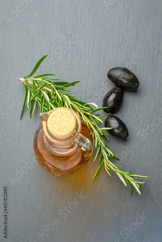 Olive oil. Olives on a background of olive oil. A bottle pours oil into a saucer close-up. Black stone table top with place for text or design