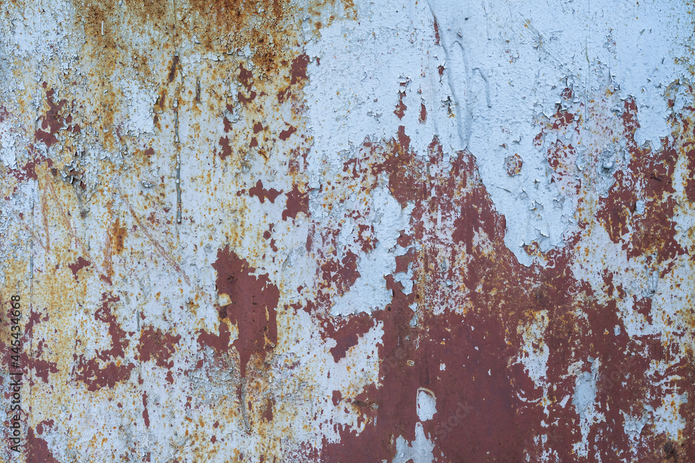 The surface of a metal wall with several crumbling paint layers and traces of rust. It looks like a satellite photograph of the earth's surface. Background. Texture.