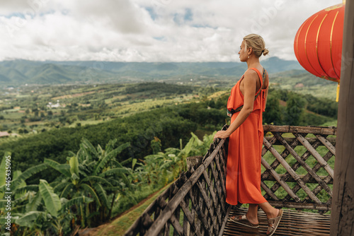 Young woman tourist in orange dress enjoying amazing view at Yun Lai Viewpoint photo