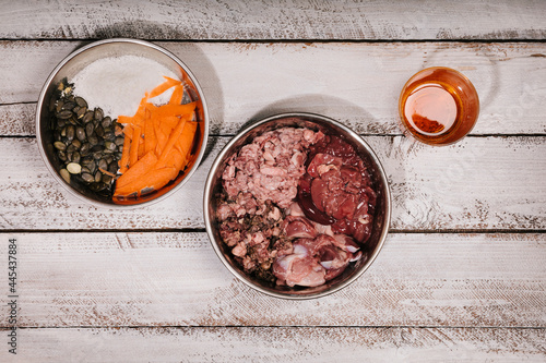 Bowls of biologically appropriate raw food (BARF), salmon oil and carrots, coconut and pumpkin seeds