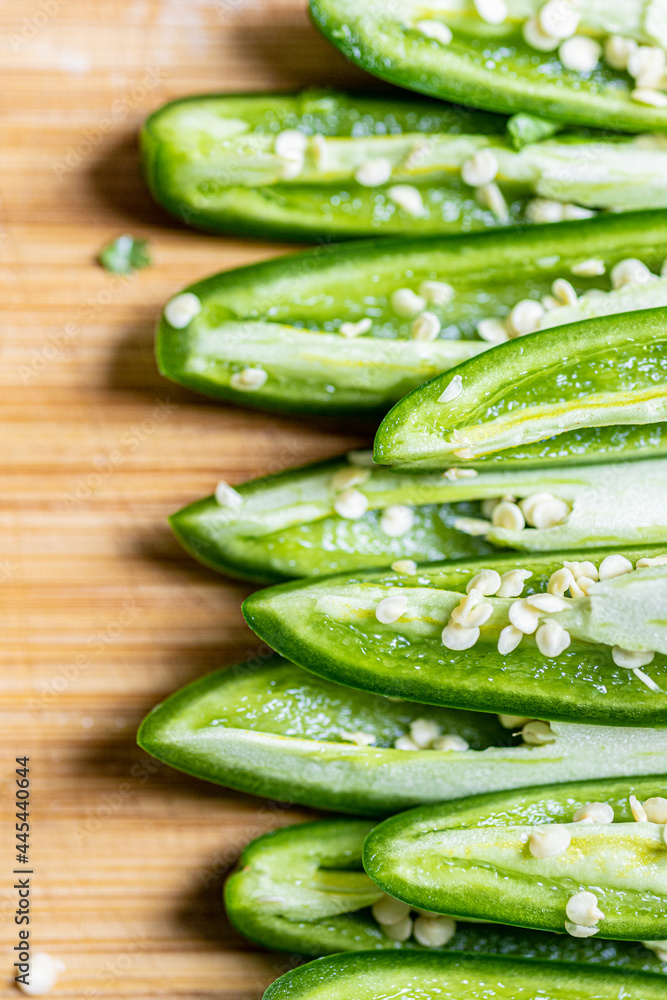 Quartered jalapenos stacked on cutting board