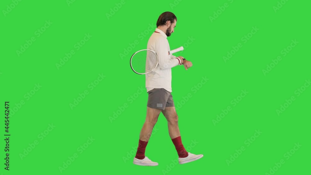 Handsome male tennis player walking and using smart watch on a Green Screen, Chroma Key. Handsome male tennis player walking and using smart watch on a Green Screen, Chroma Key.