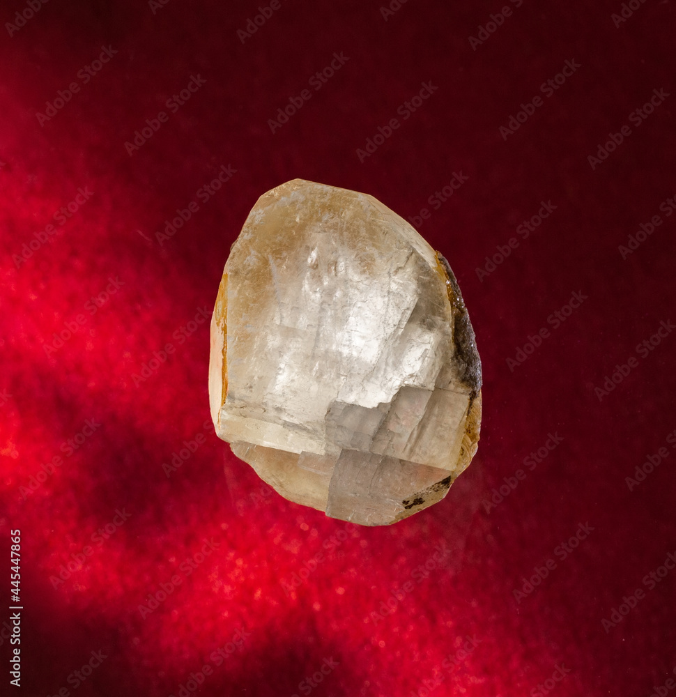 Transparent calcite mineral crystal from Ural, Russia. A backlight photo of a stone on red background. Geology websites, stone collection catalog, Natural Science museum wall chart Transparent calcite mineral crystal from Ural, Russia. A backlight photo of a stone on red background. Geology websites, stone collection catalog, Natural Science museum wall chart