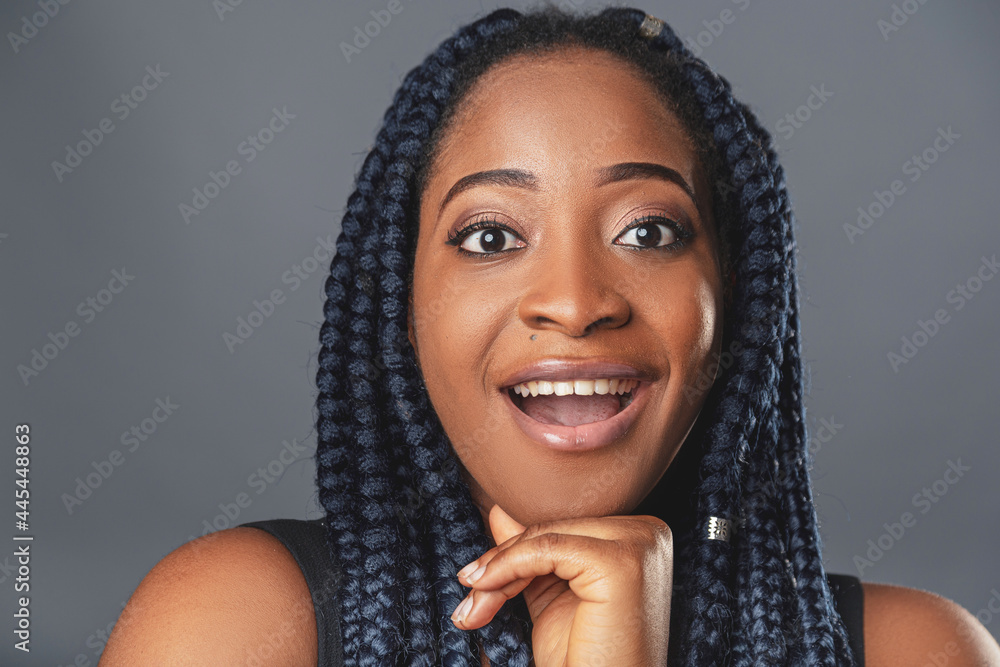 A young dark-skinned woman in a casual atmosphere looks into the camera with copy space curly black hair braided in pigtails. background color gray A young dark-skinned woman in a casual atmosphere looks into the camera with copy space curly black hair braided in pigtails. background color gray
