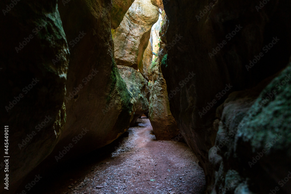 spectacular cave interior with large rocks and entrance from the top of sunlight rays.