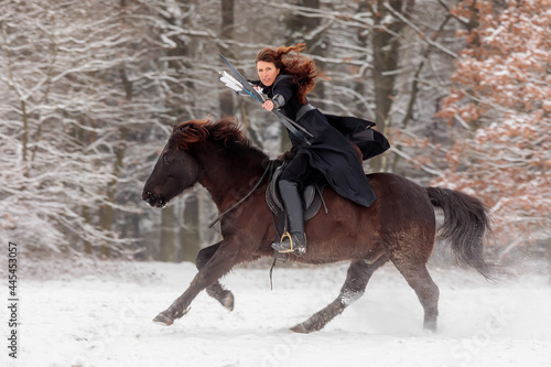a beautiful woman rides swiftly past on horseback and shoots a bow
