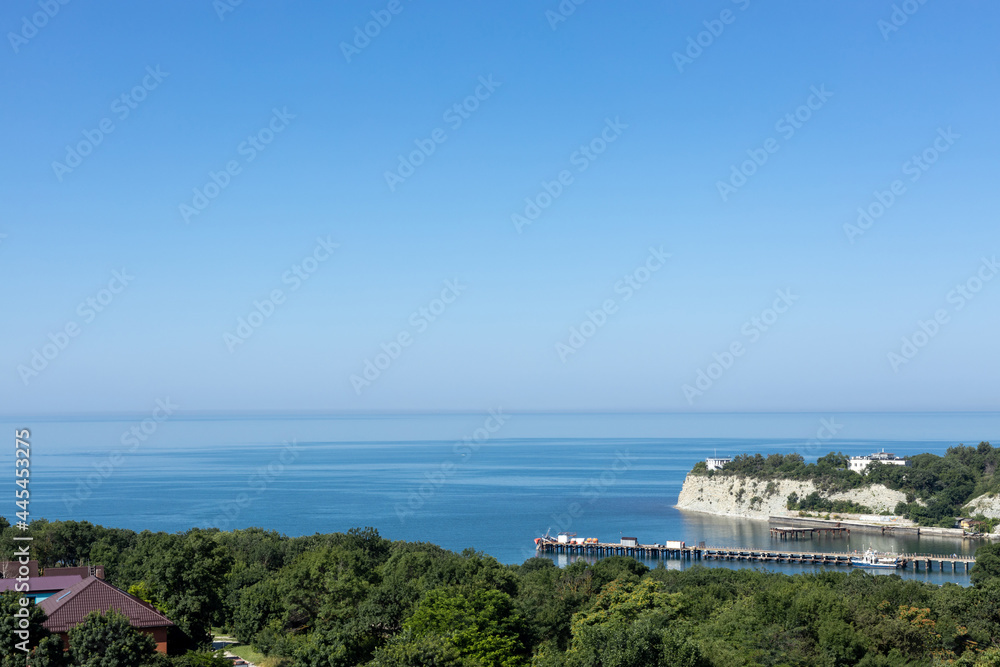 Landscape. A picturesque sea bay with rocks and forests on the coast and a pier for boats.
