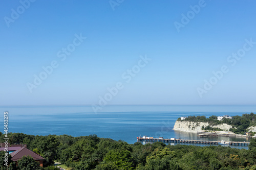 Landscape. A picturesque sea bay with rocks and forests on the coast and a pier for boats.