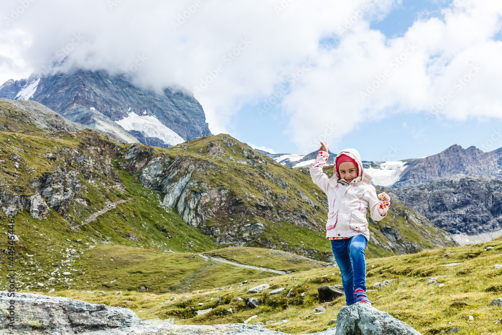 Children hiking in Alps mountains. Kids look at mountain in Austria. Spring family vacation. Outdoor fun and healthy activity.