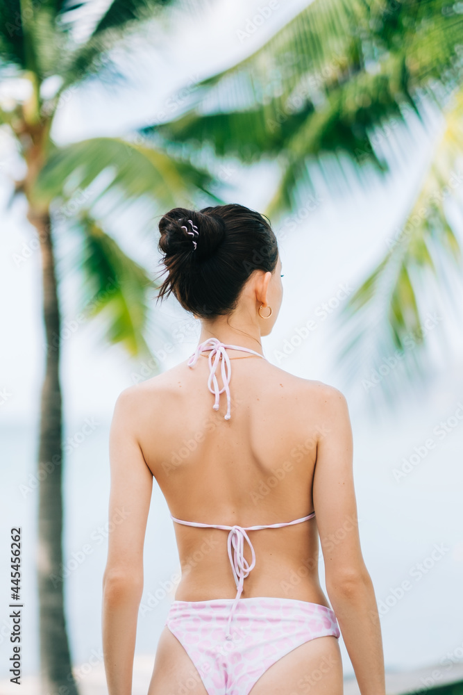 Φωτογραφία Young caucasian woman with perfect body standing on a tropical shore with palm trees on sunny day