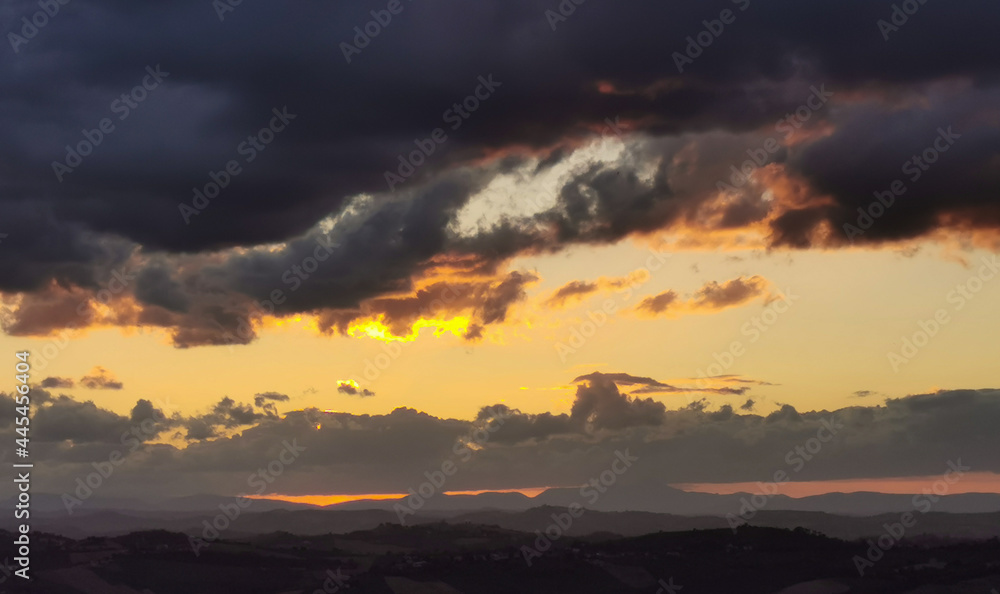 Tramonto sulle montagne e le valli dell’Appennino con grandi nuvole colorate cariche di pioggia