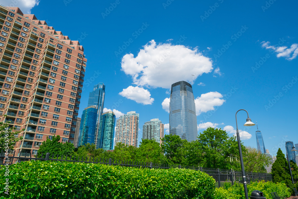 Unique shape clouds float over the Luxury high-rise apartments in Jersey City New Jersey ward and Lower Manhattan skyscraper in Manhattan ward along the promenade beside Hudson River in springtime.