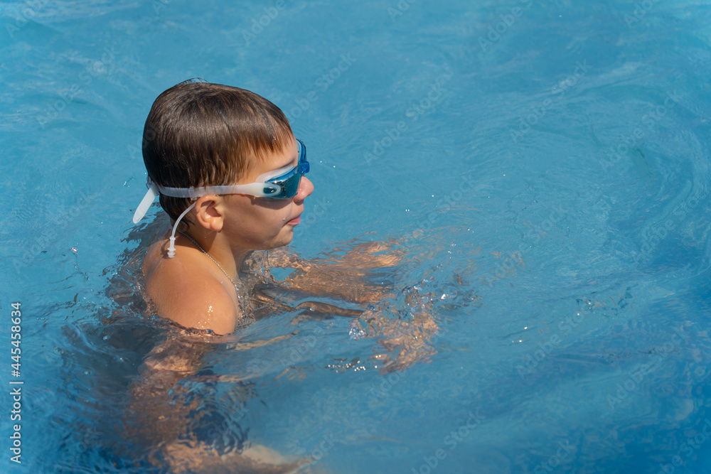 boy in swimming goggles swimming in blue water