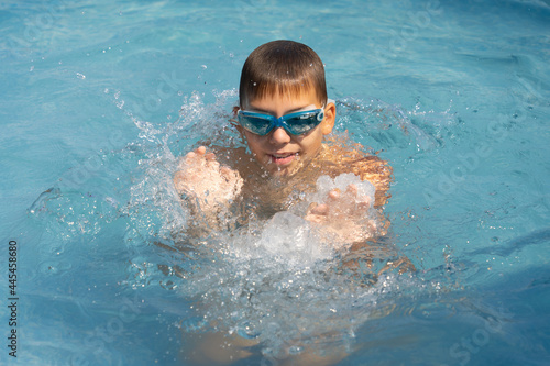 boy bathes in the pool wearing swimming goggles