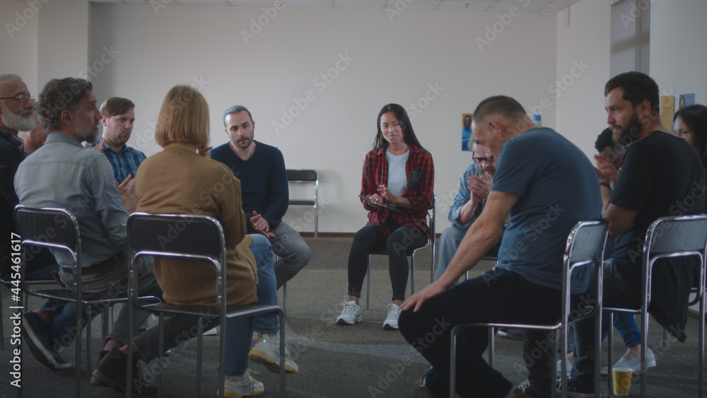 People supporting upset man during group meeting - obrazy, fototapety, plakaty 