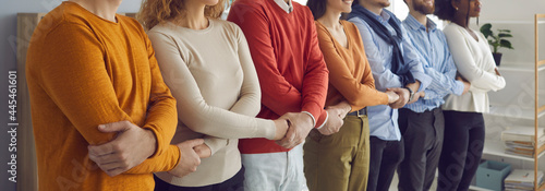 Diverse communication office, corporate cooperation. Team of people, freelance business worker or friends group holding hands tied together as chain standing in row line. Midsection shot