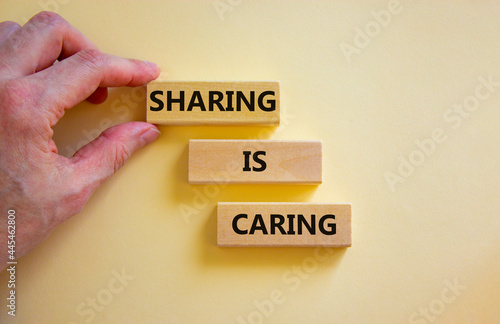 Sharing is caring symbol. Wooden blocks with words 'Sharing is caring' on beautiful white background. Businessman hand. Business, sharing is caring concept. Copy space. photo