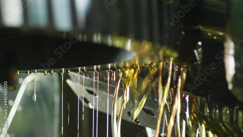 Turning and milling machine in a modern factory, automated CNC system rotates and works with water, liquids, spray, slow motion, close-up. Oil flows down the processed part.